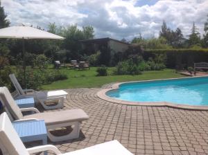 a swimming pool with two chairs and an umbrella at Rose Barn - Adorable country home with private pool in Cersay