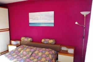 um quarto com uma parede cor-de-rosa, uma cama e um candeeiro. em Apartment Matea em Matulji