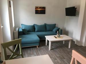 a living room with a blue couch and a table at Marijanas Ferienhof 2, Urlaub mit viel Platz zwischen Dornumersiel und Bensersiel, gehört zum Café Kunterbunt in Holtgast
