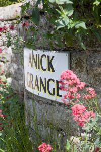 a sign on a stone wall with pink flowers at Anick Grange Farm B&B in Hexham