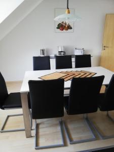 a dining room with a white table and black chairs at Ferienwohnung am Bodensee mit 3 Schlafzimmer über 2 Etage mit kleine Balkon bis 7 Personen in Überlingen