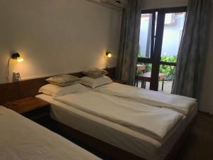 two beds in a hotel room with a window at Villa Milev in Kranevo