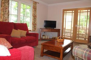 ein Wohnzimmer mit einem roten Sofa und einem Couchtisch in der Unterkunft Roualeyn in Huntly