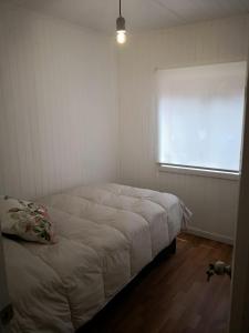 1 dormitorio con 1 cama en una habitación con ventana en Refugio Simple Sur Casa 4 - 5 personas, en Malalcahuello