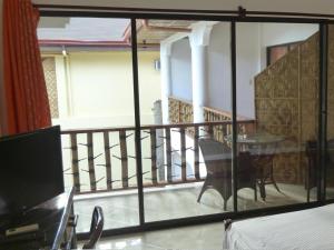 a room with a balcony with a table and a television at Alona Vida Beach Resort in Panglao