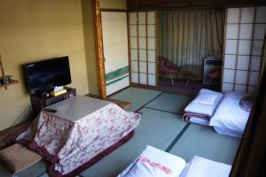 a hotel room with a bed and a tv at Miyoshiya Ryokan in Tanabe