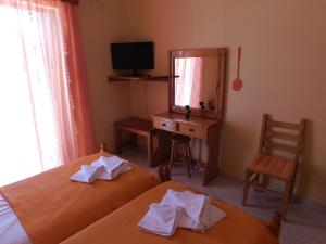 a bedroom with two beds and a desk with a mirror at To Spiti Tis Eirinis in Poros