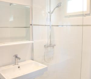 a white bathroom with a shower and a sink at Bellavistaloc' in Porto-Vecchio