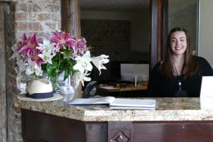 a woman sitting at a counter with a vase of flowers at The Grange Hotel Brent Knoll in Highbridge