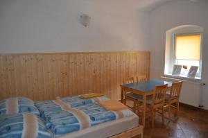 a bedroom with a bed and a table and a window at Ubytování U Tajčů in Dolní Beřkovice