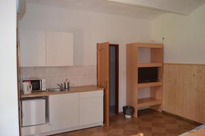 una pequeña cocina con armarios blancos y microondas en Ubytování U Tajčů, en Dolní Beřkovice