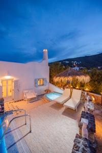 a villa with a swimming pool and a straw umbrella at Starlight Luxury Seaside Villa & Suites in Imerovigli