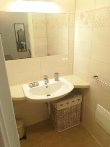 Baño blanco con lavabo y espejo en Casa Mirtillo, en Bernalda