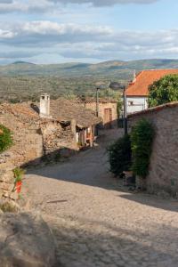 um beco num antigo edifício de pedra com montanhas ao fundo em Cidadelhe Rupestre Turismo Rural em Cidadelhe