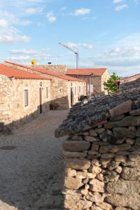 a stone wall in front of some buildings at Cidadelhe Rupestre Turismo Rural in Cidadelhe