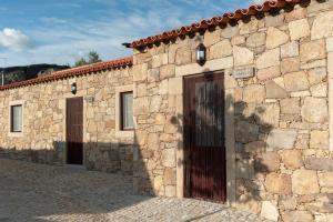 un edificio de piedra con dos puertas y una puerta en Cidadelhe Rupestre Turismo Rural, en Cidadelhe