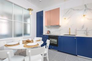 a kitchen with blue cabinets and a white table and chairs at Apartament Kopernik in Toruń