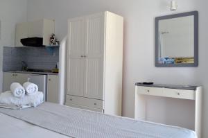 a white bedroom with a bed and a mirror at Paleochori Studios in Paliochori