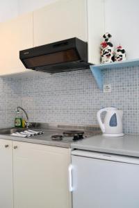 a kitchen with white cabinets and a stove top oven at Paleochori Studios in Paliochori