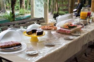 een tafel met gebak en desserts op borden bij Pousada Treze Luas in Ilha do Mel