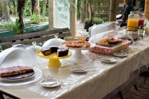 a table topped with cakes and desserts on plates at Pousada Treze Luas in Ilha do Mel