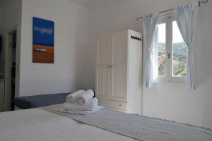 a white bedroom with a bed and a window at Paleochori Studios in Paliochori