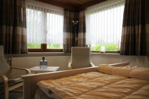 a bedroom with a bed and two chairs and windows at Bungalow am Forsthaus Stagnieß in Ueckeritz