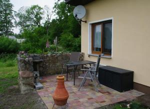 un patio con mesa y sillas junto a una casa en Bungalow am Forsthaus Stagnieß en Ueckeritz