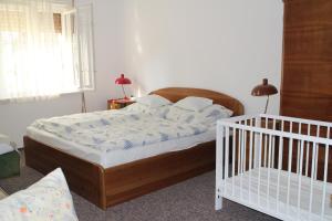 a bedroom with a bed and a crib at Evelin Nyaralóház in Siófok