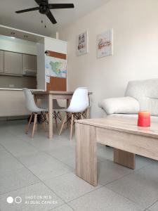 ein Wohnzimmer mit einem Tisch, Stühlen und einem Sofa in der Unterkunft ApartaClub la Barrosa in Chiclana de la Frontera
