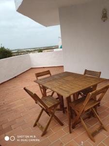 einen Holztisch und Stühle auf einer Terrasse in der Unterkunft ApartaClub la Barrosa in Chiclana de la Frontera