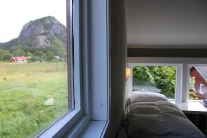 a bedroom window with a view of a field at Camp Åpta in Farsund