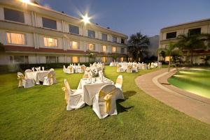 Habitación con mesas y sillas blancas frente a un edificio en Hotel Express Residency-Jamnagar, en Sika