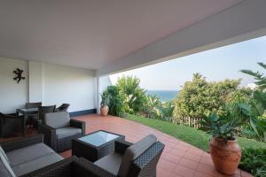 a patio with chairs and tables and a view of the ocean at Long Island 19 in Ballito