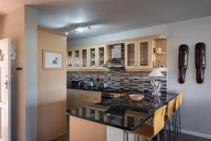 a kitchen with a black counter top and wooden cabinets at Long Island 19 in Ballito