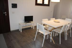 una sala da pranzo con tavolo, sedie e televisione di Boa Vista Favignana - Home&Beach a Favignana