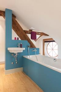 a bathroom with a white tub and a sink at Kulturhotel Guggenheim in Liestal