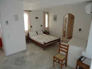 a bedroom with a bed and a chair in it at Zorbas Hotel & Studios in Pythagoreio