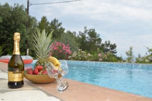 een fles champagne en een fruitmand naast het zwembad bij Sarakiniko villa with private pool in Póros