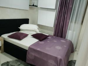 1 cama con sábanas y almohadas moradas en una habitación en Apartament Luk Twin Loft, en Mamaia