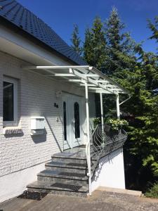 a white pergola on a house with stairs at Studio, Nähe Dieksee in Malente +6 photos