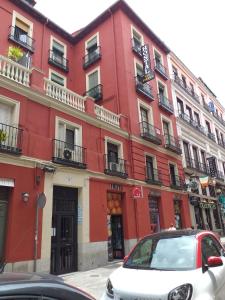 Hostal Río Paraná في مدريد: مبنى احمر فيه سيارة بيضاء تقف امامه