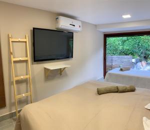 a room with two beds and a flat screen tv at Canto das Acácias in Fernando de Noronha