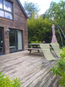 a deck with an umbrella and a table and a chair at Un Jardin en Pente Douce in Locquénolé