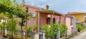 ファジャナにあるModern Holiday Home with pool & 4 bikes, near centerの塀とブドウの木が植えられたピンクの家