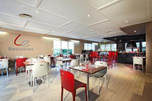 un restaurante con mesas y sillas rojas y blancas en Campanile Grenoble Nord - Moirans-Voreppe en Moirans