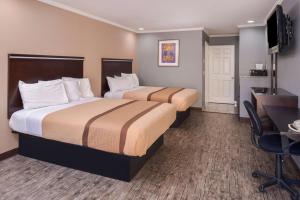 a hotel room with two beds and a desk at Laguna Inn and Suites in San Juan Capistrano