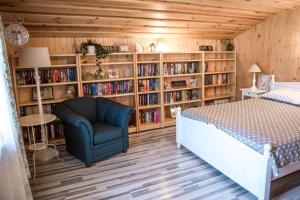 a bedroom with a bed and a chair and book shelves at Flower apartment in Ventspils