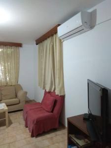 uma sala de estar com uma cadeira vermelha e uma televisão em Anastasia' s guest house em Neos Marmaras