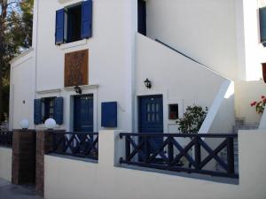 a white building with blue doors and a railing at 5bedroom villa in perissa beach in Perissa